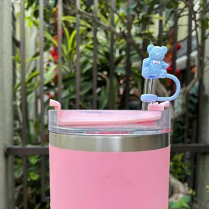 Pink stainless steel tumbler detail shot with cute blue smiley bear silicone straw topper.
