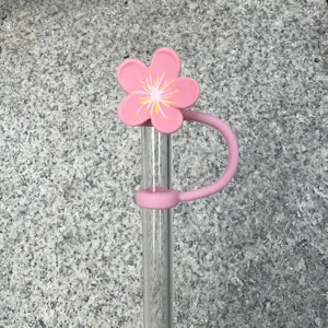 Close-up of cute pink cherry blossom silicone straw cover and clear glass straw detail.