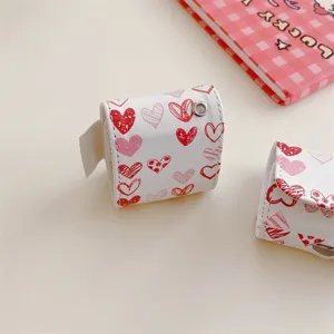 Detailed view of white leather AirPods case featuring cute red and pink sketch heart patterns.