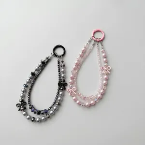Detailed view of handmade beaded phone strap with cute bow and crystal pearls, anti-drop accessory.