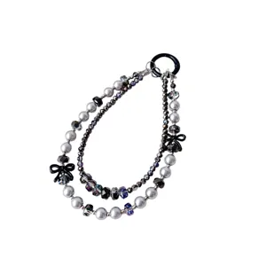 Close-up detail of double-strand beaded phone charm with grey pearls and black bows.