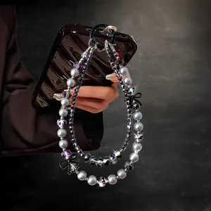 Detailed view of luxury crystal and pearl phone strap with cute black bows and double chains.