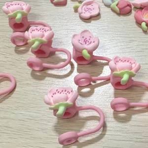 Close-up detail of pink peach flower silicone straw covers and stopper accessories for cups.