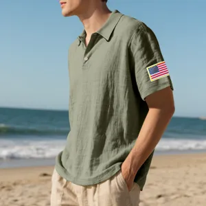 Close-up view of the breathable linen polo shirt with flag patch on beach background.