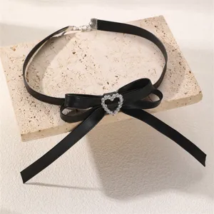Schwarze Leder-Choker-Halskette mit eleganter Schleife und glitzerndem Strass-Herz-Detail.