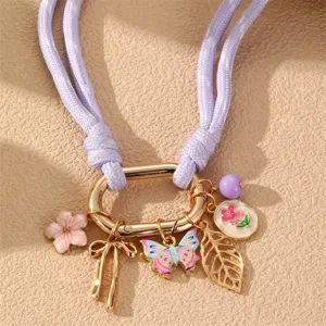 Nahaufnahme Detail einer violetten geflochtenen Halskette mit bunten Blumen und Schmetterlingen.