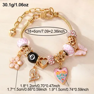 Detailansicht des goldenen Charm-Armbands mit rosa Perlen und verschiedenen Anhängern.
