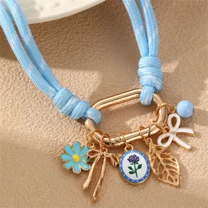 Schönes hellblaues geflochtenes Seil-Halsband Detail mit Blumen- und Schleifen-Anhängern.