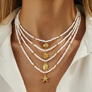 Detailaufnahme der eleganten mehrlagigen Perlenkette mit goldenen Meeresanhängern.