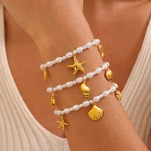 Detailaufnahme des mehrschichtigen Perlenarmbands mit goldenen Muschel und Seestern Anhängern.