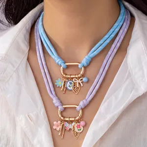 Nahaufnahme der mehrlagigen Kordelkette mit bunten Anhängern in Pastellblau und Lila.