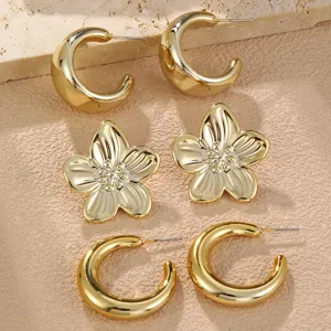 Schickes goldenes Ohrring-Set mit klobigen C-förmigen Creolen und Blumen-Ohrringen.