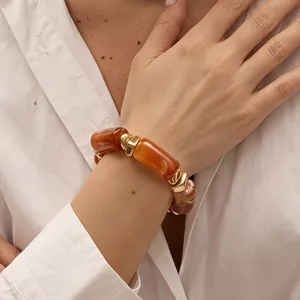 Klobiges orangefarbenes Harz- und Gold-Geometric-Metallarmband Detail, modischer Schmuck.