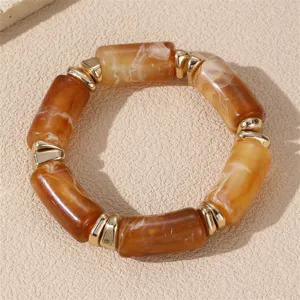 Klobiges Armband aus bernsteinfarbenen Harzperlen mit goldfarbenen Metallabstandshaltern.