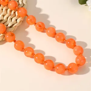 Collana con perle acriliche arancioni dettaglio primo piano, moda gioielli stile bohémien.