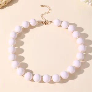 Elegante collana statement con perle acriliche bianche e chiusura dorata da donna.