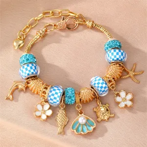 Goldfarbenes Ozean-Charme-Armband mit blauen karierten Perlen und süßen Meeresanhängern.