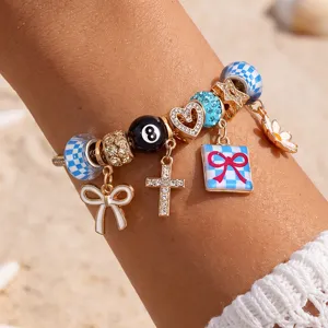 DIY Charm Armband mit blauen Karopellen, Kreuz, Schleife und 8-Ball Anhängern für Damen.