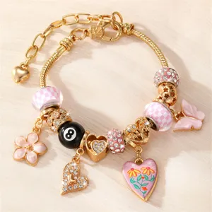 Detaillierte Nahaufnahme des goldenen DIY-Charm-Armbands mit rosa und glitzernden Anhängern.