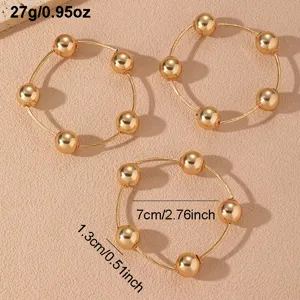 Vista detallada de cerca de tres elegantes pulseras apilables de metal en tono dorado.