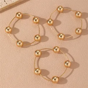 Detalle en primer plano del set de pulseras doradas con cuentas pulidas y cadenas finas.