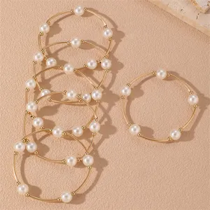 Detalles exquisitos del conjunto de pulseras de perlas apiladas doradas, artesanía fina.