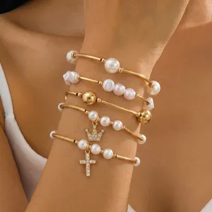 Primer plano detallado del conjunto de pulseras doradas multicapa con perlas y cruces.