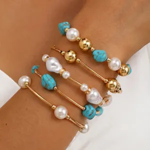 Vista detallada del conjunto de pulseras multicapa con barras doradas, perlas y turquesas.
