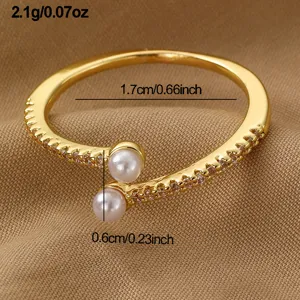 Goldener Offener Ring Detail mit zarten Perlen und funkelnden Zirkoniasteinen auf Stoff.
