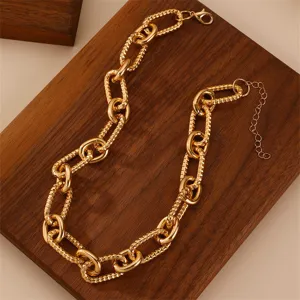 Closeup of chunky gold chain necklace showing textured links and adjustable clasp details.