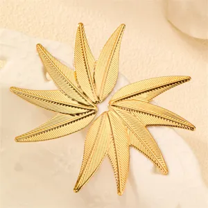 Nahaufnahme von goldenen Metall Ahornblatt Ohrringen, einzigartiges Pflanzendesign für Frauen.