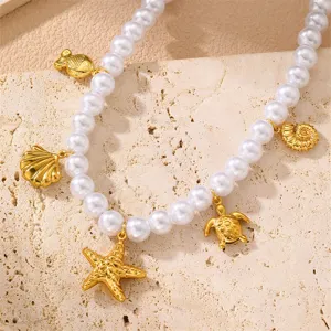 Nahaufnahme der Perlenkette mit goldenen Meeresanhängern wie Seestern und Muscheln.
