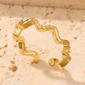 Nahaufnahme eines schicken goldenen Wellenrings mit funkelnden Zirkoniasteinen.