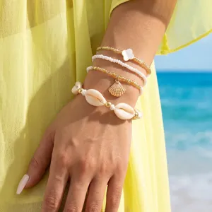 Λεπτομερής λήψη σετ πολυεπίπεδων boho βραχιόλων με κοχύλια και χάντρες για την παραλία.