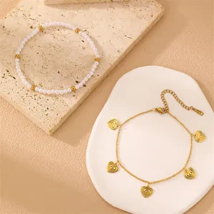 Detaillierte Nahaufnahme von Perlen und goldenen Herzanhänger Armbändern auf Display.