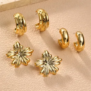 Nahaufnahme der eleganten goldenen Metall Creolen und floralen Ohrstecker mit feiner Struktur.