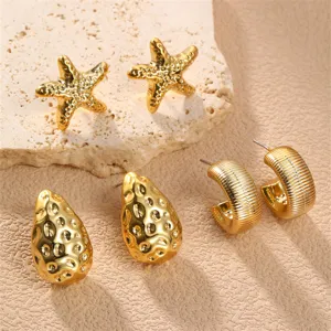 Nahaufnahme Detail des goldnen Metall Ohrring Sets mit Seestern, Tropfen und Creolen.