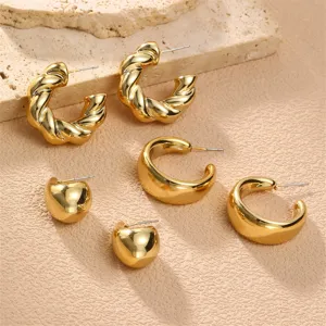 Detailansicht des goldenen Metall-Ohrring-Sets mit trendigen verdrehten und klobigen Creolen-Designs.