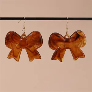 Detailansicht eleganter brauner Schildpatt-Schleifen-Ohrringe mit goldenen Haken für Damen.