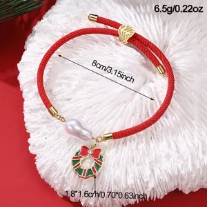 Nahaufnahme des roten Weihnachts-Armbands mit Perle und Kranz-Anhänger, Detailansicht.