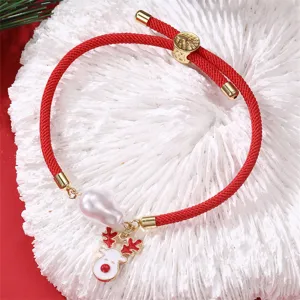Rotes geflochtenes Weihnachtsarmband Detail mit weißer Barockperle und Rentieranhänger.