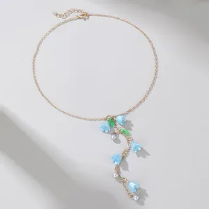 Detailed shot of the gold-tone chain necklace featuring blue bellflower and pearl pendants.