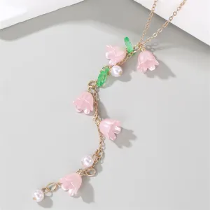 Close-up detail of the elegant pink lily of the valley pendant and pearl charm necklace.
