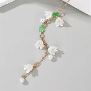 Gold Y-shaped necklace featuring white lily of the valley flowers, pearls, and green leaves.