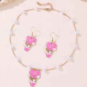 Detail shot of pink enamel heart hot air balloon necklace and earrings set with faux pearls.