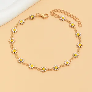 Gold tone metal anklet featuring enamel daisy charms with white petals and yellow centers.