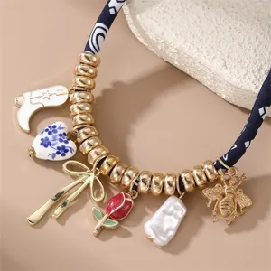 Mehrere Anhänger Schlüsselbeinkette mit dunkelblauem Samtband und goldenen Perlen sowie Details.