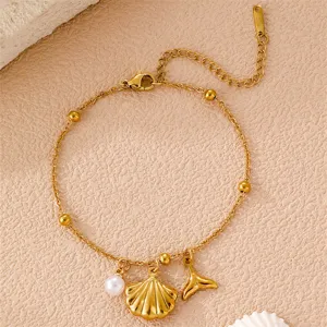 Nahaufnahme von goldener Muschel und Wal-Anhänger an einem eleganten Boho Perlenarmband.