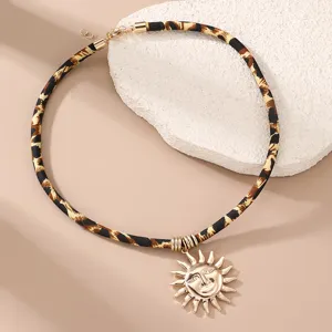 Leopardenmuster Samt Kordel Kette mit goldenem Sonnen Gesicht Anhänger, modischer Schmuck Detail.