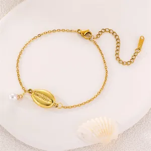 Nahaufnahme Detail der goldfarbenen Kette Armband mit Muschel Anhänger und Perlen.